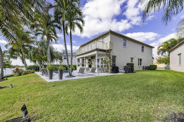 rear view of property with a yard, a patio, and a balcony