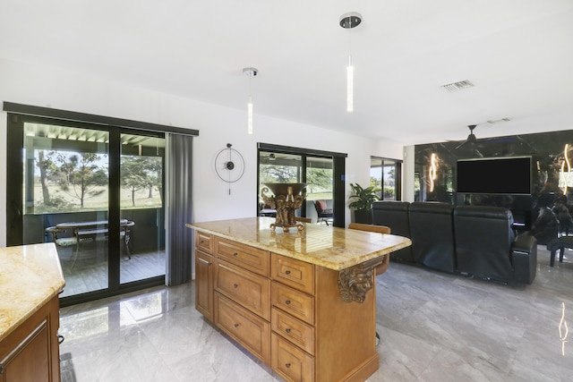 kitchen featuring decorative light fixtures, a center island, and light stone countertops