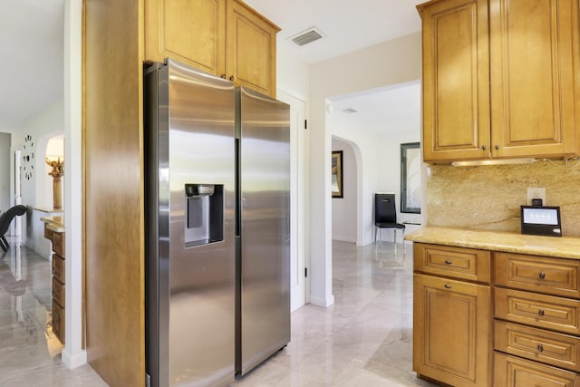 kitchen featuring decorative backsplash, light stone counters, and stainless steel fridge with ice dispenser