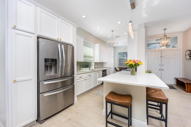 kitchen with pendant lighting, a breakfast bar, white cabinetry, and stainless steel appliances