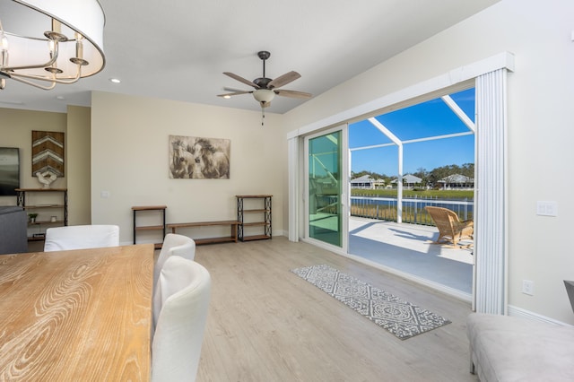 interior space featuring ceiling fan with notable chandelier and light hardwood / wood-style flooring