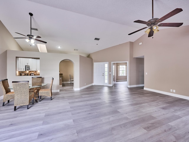 living room featuring a textured ceiling, high vaulted ceiling, light hardwood / wood-style flooring, and ceiling fan