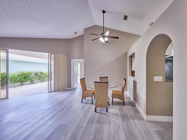 dining space featuring ceiling fan, light wood-type flooring, a textured ceiling, and high vaulted ceiling