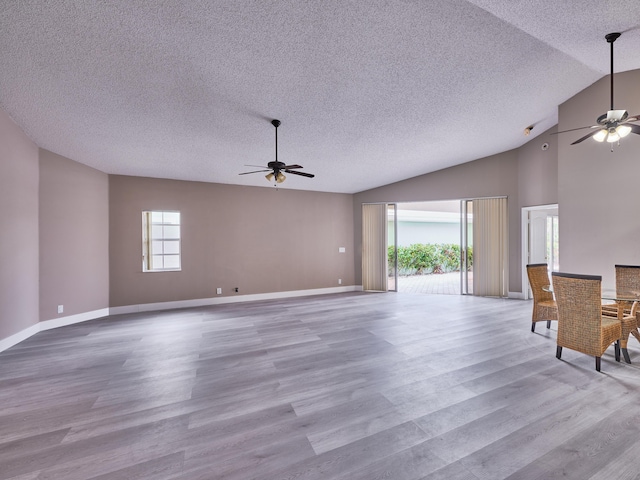 unfurnished living room with ceiling fan, light hardwood / wood-style floors, lofted ceiling, and a textured ceiling