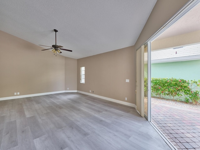 unfurnished room with ceiling fan, a textured ceiling, and light wood-type flooring