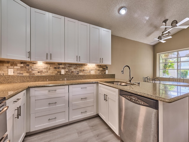 kitchen featuring white cabinetry, sink, stainless steel dishwasher, kitchen peninsula, and a textured ceiling