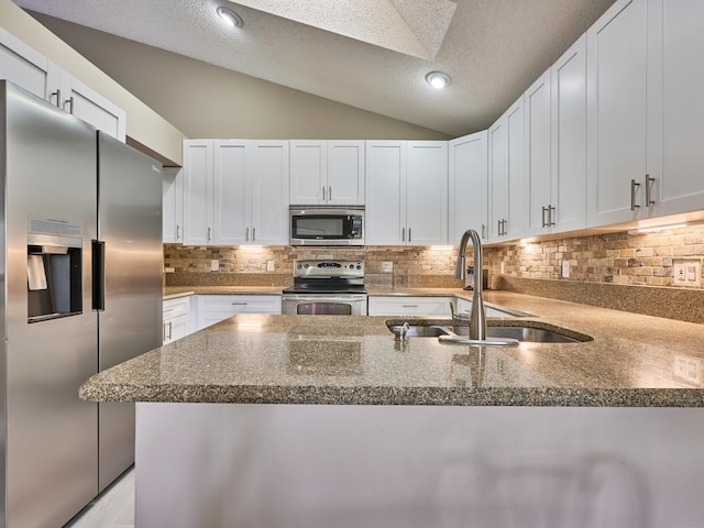 kitchen featuring a textured ceiling, white cabinets, stainless steel appliances, and vaulted ceiling