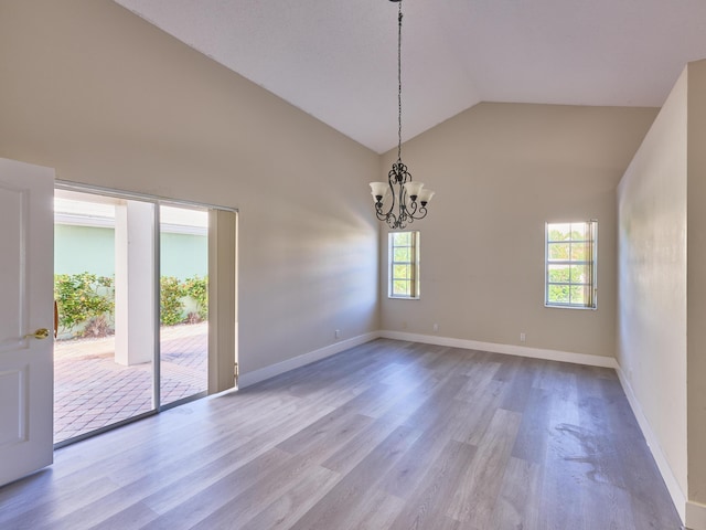 unfurnished room featuring a chandelier, light hardwood / wood-style floors, and high vaulted ceiling