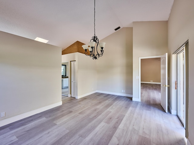 unfurnished dining area with a notable chandelier, high vaulted ceiling, and light hardwood / wood-style flooring