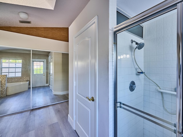 bathroom with hardwood / wood-style flooring, an enclosed shower, a textured ceiling, and vaulted ceiling