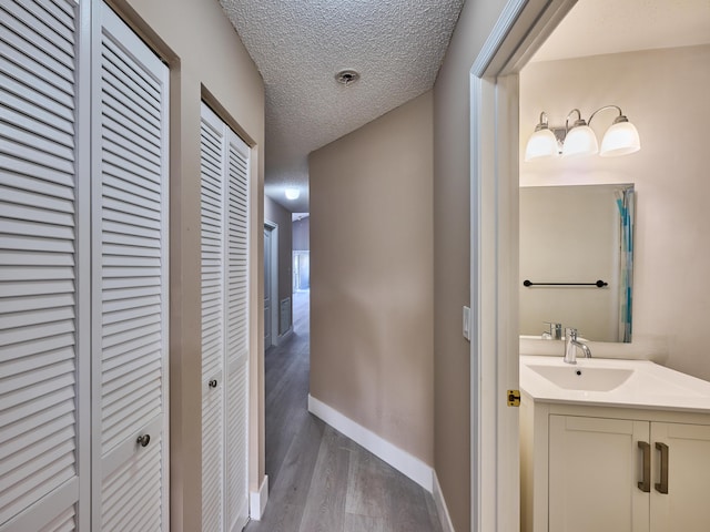 bathroom with hardwood / wood-style floors, vanity, and a textured ceiling