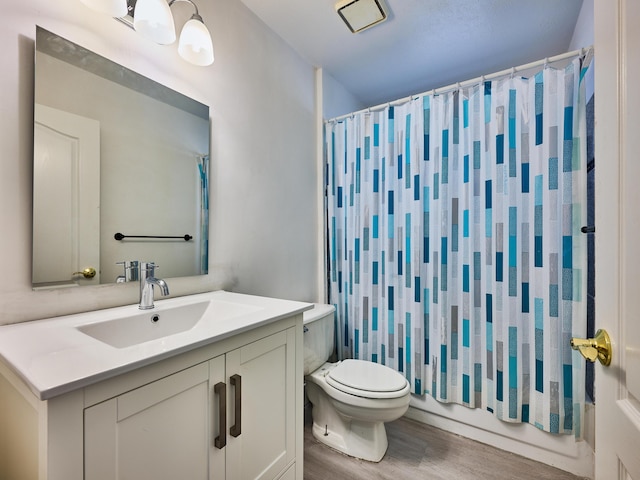 full bathroom featuring wood-type flooring, vanity, shower / tub combo, and toilet