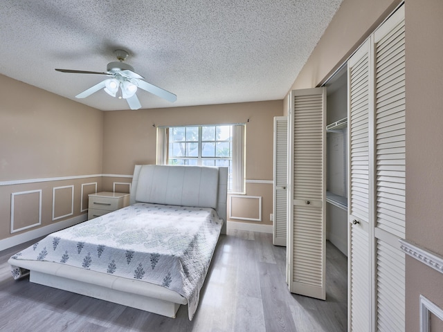 bedroom with a textured ceiling, hardwood / wood-style flooring, and ceiling fan