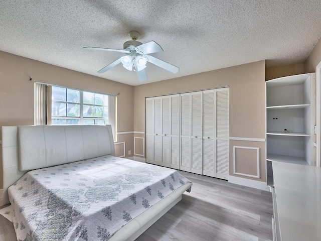 bedroom with ceiling fan, light wood-type flooring, a textured ceiling, and a closet