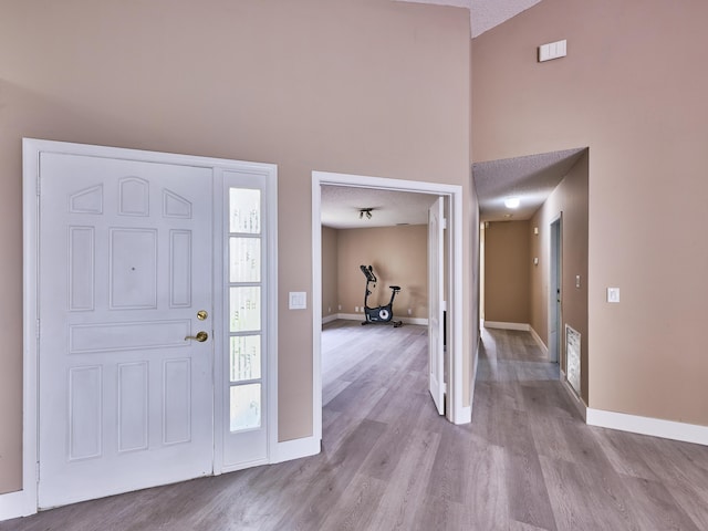 foyer featuring vaulted ceiling, a textured ceiling, and light wood-type flooring