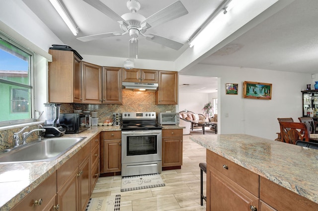 kitchen featuring light stone countertops, electric range, tasteful backsplash, and sink