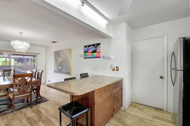 kitchen featuring kitchen peninsula, a kitchen breakfast bar, stainless steel refrigerator, and hanging light fixtures