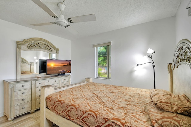 bedroom featuring ceiling fan, light hardwood / wood-style floors, and a textured ceiling