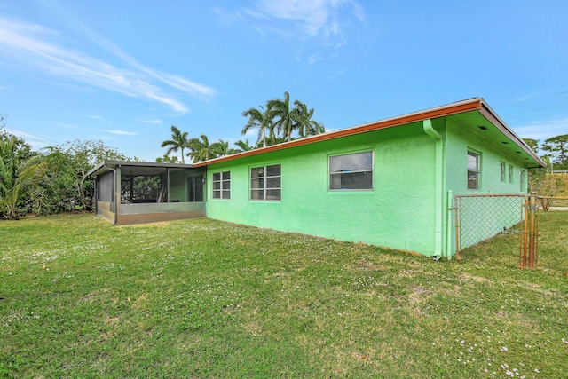 rear view of property featuring a lawn and a sunroom