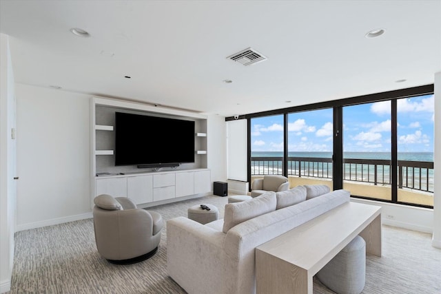 living room with a healthy amount of sunlight, light colored carpet, and a wall of windows