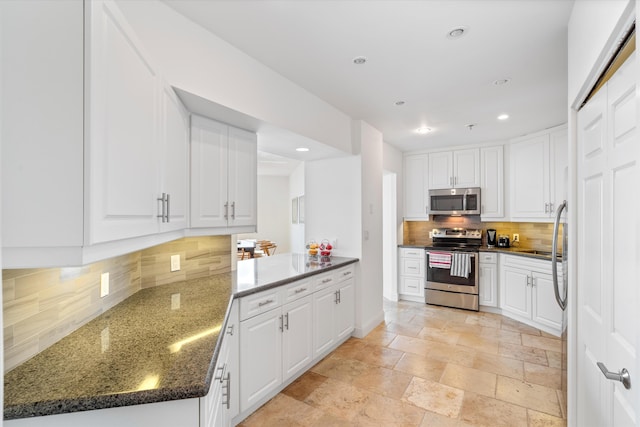 kitchen featuring white cabinets, kitchen peninsula, appliances with stainless steel finishes, and tasteful backsplash