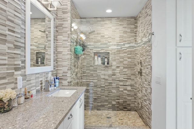 bathroom featuring backsplash, vanity, and tiled shower