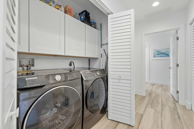 laundry area featuring cabinets, light wood-type flooring, and washer and clothes dryer