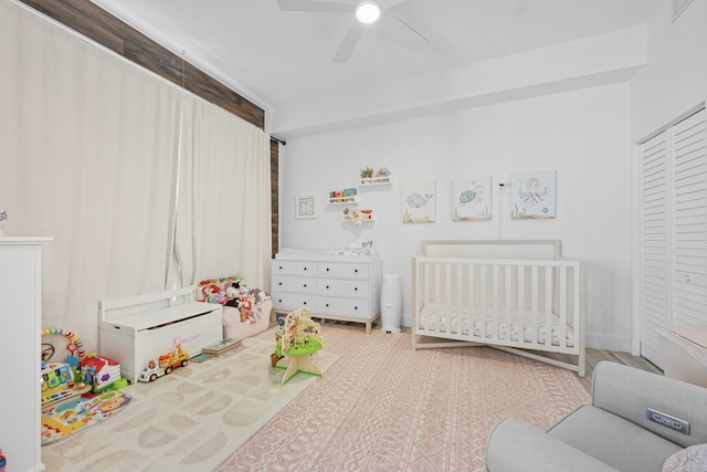 bedroom with ceiling fan, a closet, and a crib