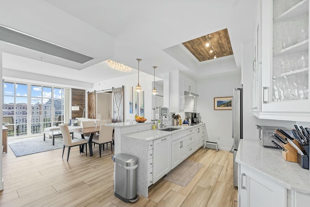 kitchen featuring white cabinets, light hardwood / wood-style floors, hanging light fixtures, and sink