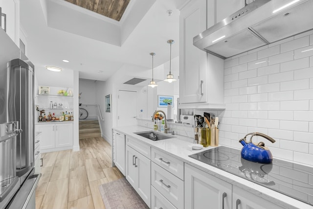 kitchen with white cabinetry, sink, hanging light fixtures, high end refrigerator, and range hood