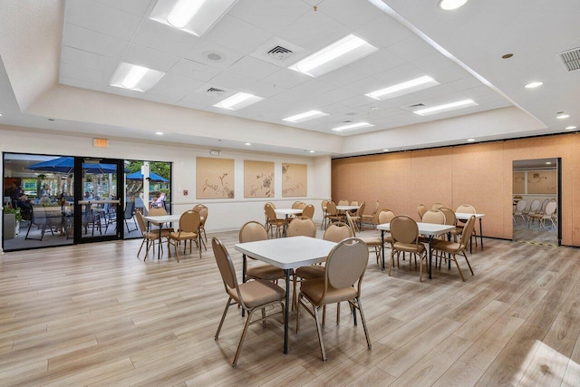 dining area featuring a paneled ceiling, light wood-type flooring, and a tray ceiling