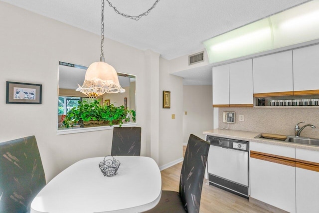 dining space with sink, a textured ceiling, and light wood-type flooring