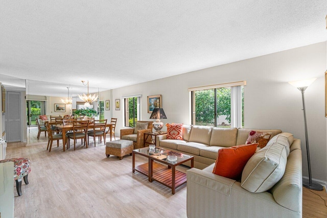 living room featuring a wealth of natural light, light hardwood / wood-style flooring, a textured ceiling, and an inviting chandelier