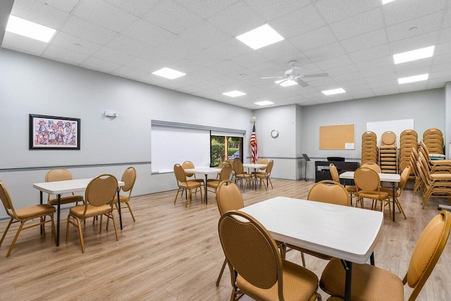 dining space featuring light hardwood / wood-style floors, a drop ceiling, and ceiling fan