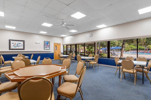 carpeted dining area with a paneled ceiling and ceiling fan