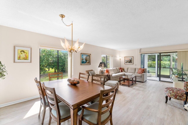 dining space featuring light wood-type flooring, plenty of natural light, and a notable chandelier