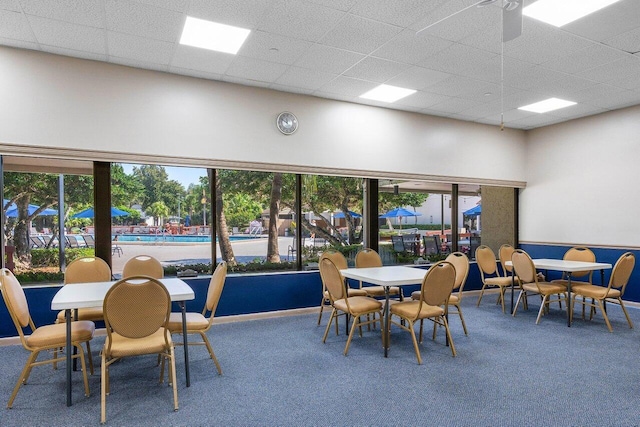 carpeted dining area featuring a paneled ceiling