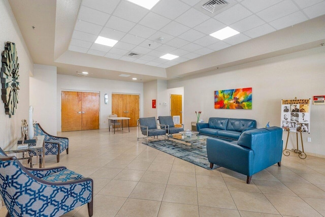 living room with a drop ceiling and light tile patterned floors