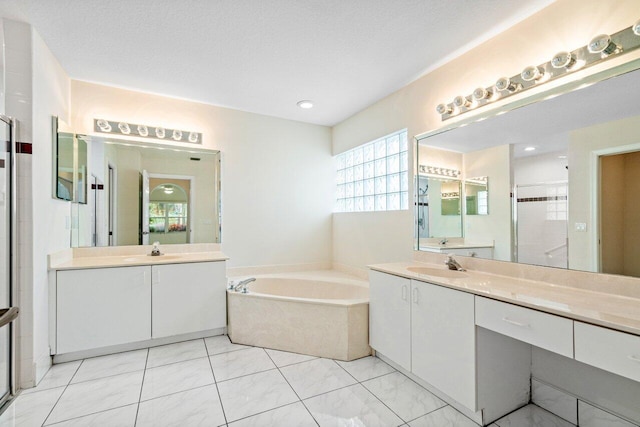 bathroom with a textured ceiling, vanity, and separate shower and tub