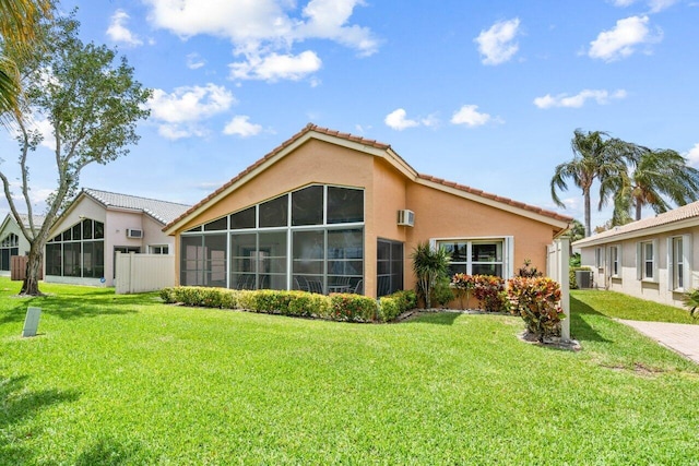 back of property featuring a sunroom, central air condition unit, and a lawn