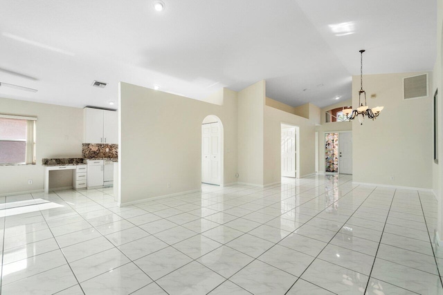 tiled empty room with lofted ceiling and an inviting chandelier