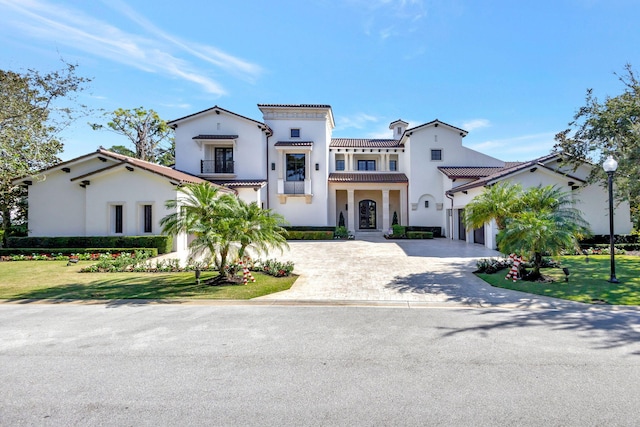 mediterranean / spanish-style home featuring a garage, a balcony, and a front yard