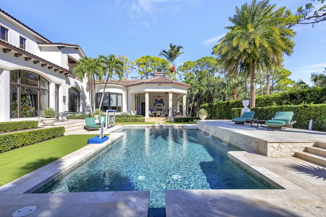 view of swimming pool with ceiling fan, pool water feature, and a patio