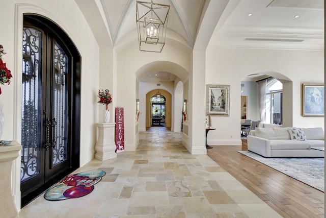 foyer entrance featuring a notable chandelier, ornamental molding, light hardwood / wood-style flooring, and french doors