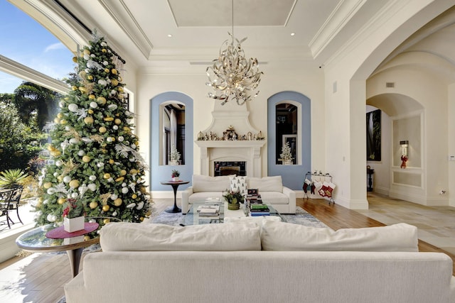 living room featuring a raised ceiling, crown molding, light hardwood / wood-style floors, and an inviting chandelier