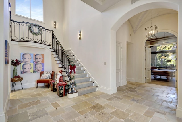 foyer featuring a notable chandelier, a towering ceiling, and pool table