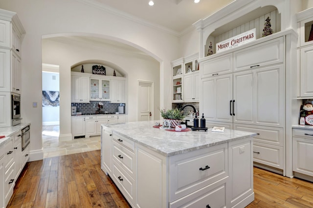 kitchen featuring white cabinets, an island with sink, and light wood-type flooring