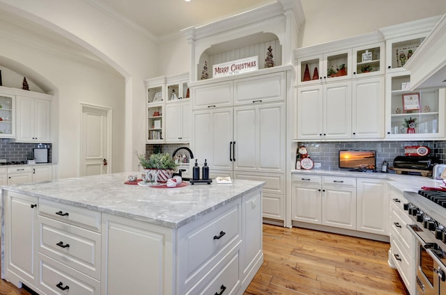 kitchen with white cabinets, light wood-type flooring, and backsplash