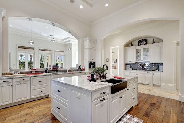 kitchen with a center island with sink, white cabinetry, and light wood-type flooring