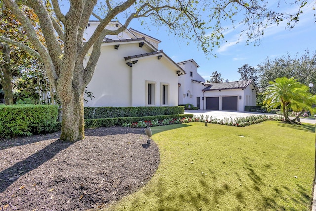 mediterranean / spanish home featuring a garage and a front lawn